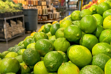 fresh, bright green limes stacked in the produce section of a grocery store