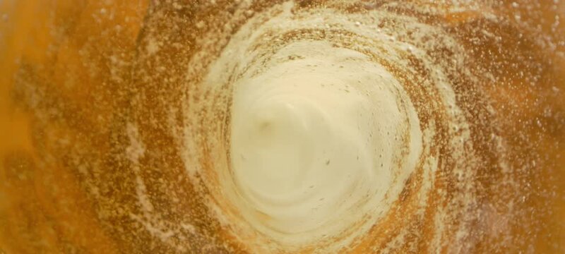 Super slow-motion shot of fresh beer whirling inside glass bottle. Macro shooting at 1000fps