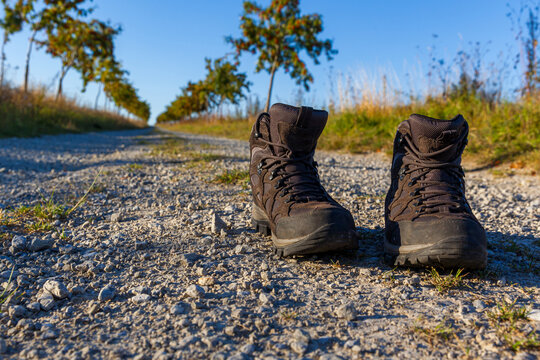 Wanderschuhe im Abendlicht auf einen Feld fotografiert Symbolbild zum Thema wandern