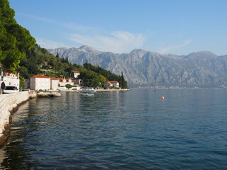 Fototapeta premium Beautiful panoramic view of the Bay of Kotor and embankment of Perast, Montenegro. Calm water and mountains on a sunny day