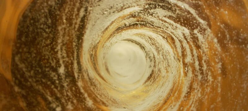 Water vortex swirling counterclockwise in slow-motion - Top view from the inside of a glass bottle