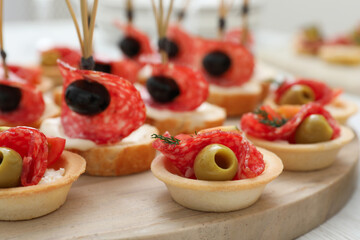 Many different tasty canapes on white wooden table, closeup