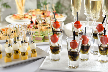 Many different tasty canapes and wine on white table, closeup