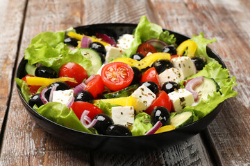 Delicious fresh Greek salad on wooden table, closeup