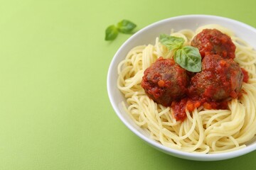 Delicious pasta with meatballs in bowl on green table, closeup. Space for text