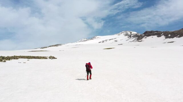 4K aerial drone footage of a lone hiker snow-covered summits of Mount Aragats, the highest peak in Armenia in spring. Breathtaking views of rugged highlands, glaciers, and remote wilderness