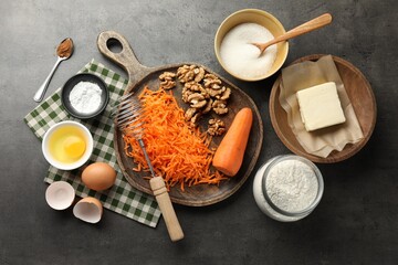 Different ingredients for making carrot cake and kitchenware on dark textured table, flat lay