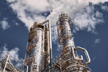 Modern chemical plant showcasing distillation columns against a bright blue sky during daytime...