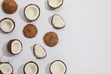 Pieces of cracked coconuts on light background, flat lay. Space for text