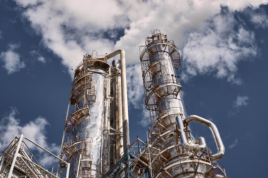 Modern chemical plant showcasing distillation columns against a bright blue sky during daytime operations in an industrial setting