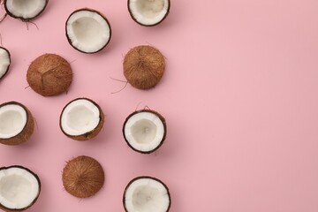 Pieces of cracked coconuts on pink background, flat lay. Space for text