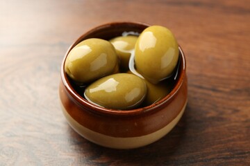 Tasty marinated olives on wooden table, closeup
