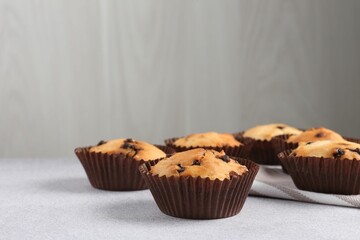 Delicious muffin with chocolate chips on light grey table, closeup