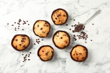 Delicious muffin with chocolate chips on white marble table, flat lay