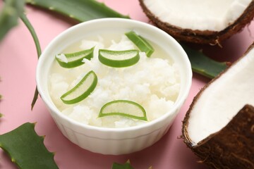 Hair treatment. Coconut butter with aloe leaves on pink background, closeup