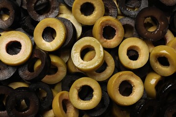 Marinated green and black olive rings as background, top view