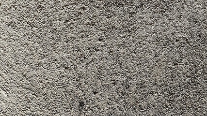 rough and mottled surface texture. The surface appears light gray with slightly darker color variations in some areas, giving the impression of three dimensions and shadows
