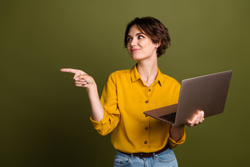 Young businesswoman with a laptop, gesturing confidently against a khaki background