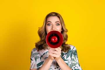 Obraz premium Young woman with a red megaphone against a bright yellow background creating an expressive communication concept