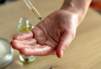 close-up of woman's hands with pipette and hand care oil. girl rubbing oil on palms, beauty,...