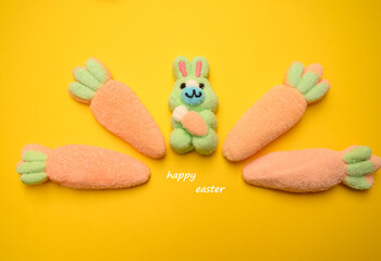 Marshmallow Easter bunny surrounded by large marshmallow carrots on a yellow background. Cute and...