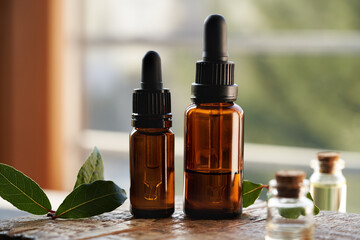 Two dark bottles of aromatherapy essential oil with fresh bay leaf