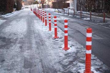 Road sign flexible plastic bollards with pedestrian white marking line and arrow sign on cement floor in parking car park area at the winter	
