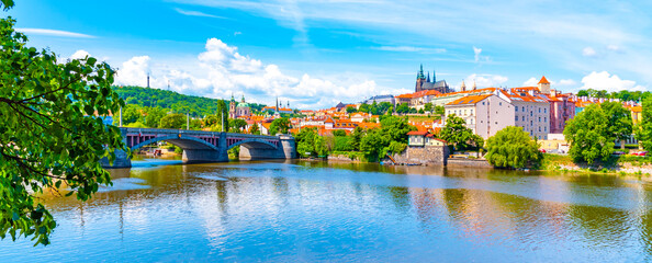 A vibrant view capturing the historic Prague Castle and Manes Bridge on a sunny day with clear...