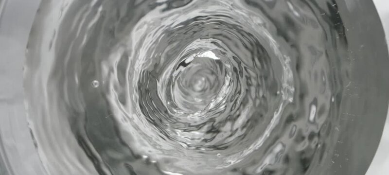 Close-up locked down shot of a water vortex drawing in a spiral shape. High quality 4k footage