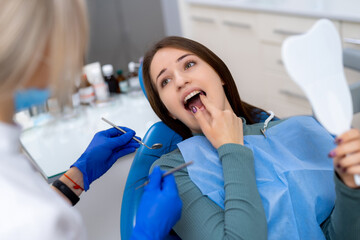 Dental checkup with a happy patient. A young woman smiles while receiving dental care in a modern...