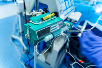 Medical tools in use. A medical device displays dosage settings while a gloved hand prepares for a...
