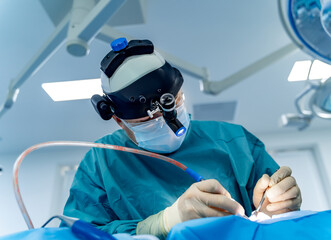 Surgeons execute complex surgery. A surgeon focuses on a delicate operation while wearing a...