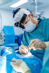 Surgeon at work in OR. A skilled surgeon focuses on a delicate operation while wearing protective...