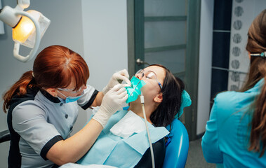 Modern dental checkup. A patient receives dental care while seated in a blue chair at a...