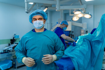 Surgeon prepares for a complex procedure. A surgeon stands ready in a sterile environment, focused on the procedure unfolding in the operating room behind him.