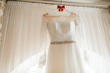 Elegant wedding dress displayed indoors. A beautiful wedding dress hangs gracefully indoors, showcasing intricate lace details and an elegant silhouette.