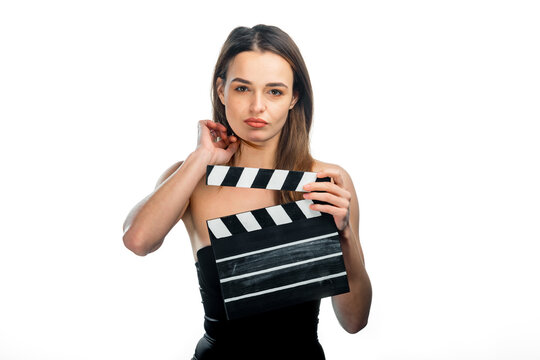 Woman with a clapperboard. A woman poses with a clapperboard, preparing for a filming session in a bright, minimalist setting.