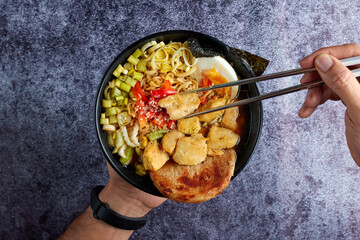 Chef preparing delicious ramen with chicken, egg, and vegetables