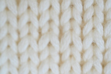 white texture of knitted wool fabric as a background, white smooth symmetrical lines of hand-knitted needlework pattern	
