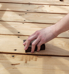 Man is polishing a wooden surface with a block of wood