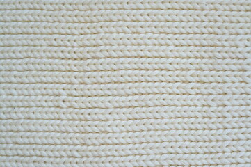 white texture of knitted wool fabric as a background, white smooth symmetrical lines of hand-knitted needlework pattern	
