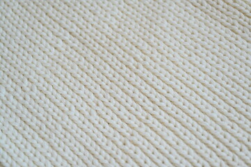 white texture of knitted wool fabric as a background, white smooth symmetrical lines of hand-knitted needlework pattern	

