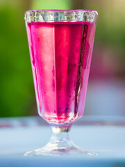 Glass of pink liquid is sitting on a table