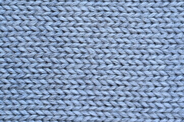 gray texture of knitted wool fabric as a background, smooth symmetrical lines of hand-knitted needlework pattern	

