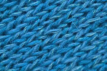 blue texture of knitted wool fabric as a background, smooth symmetrical lines of hand-knitted needlework pattern	
