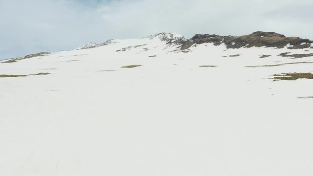 4K aerial drone footage of the snow-covered summits of Mount Aragats, the highest peak in Armenia, with its crater in spring. Breathtaking views of rugged highlands, glaciers, and remote wilderness.