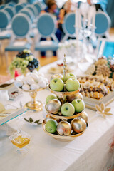 Fruit stand sits on a table near a jar of honey and colorful treats