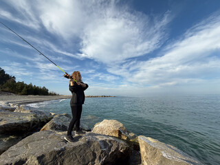 Young happy woman is fishing at sea during spring vacation