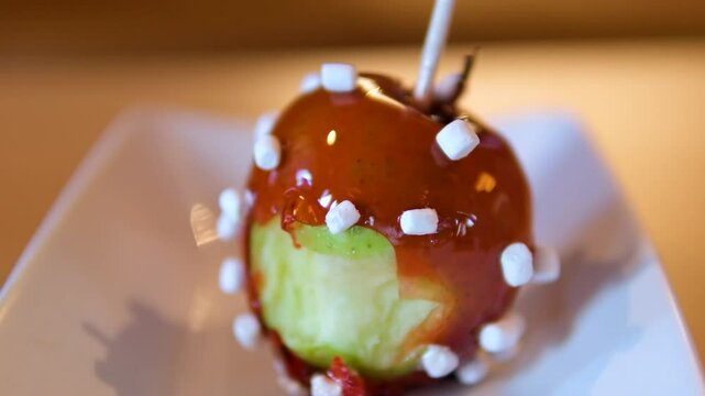Medium shot of young women eating taffy apples at amusement park. bite into a caramel apple
