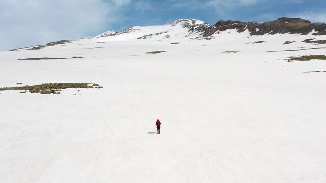 4K aerial drone footage of a lone hiker snow-covered summits of Mount Aragats, the highest peak in Armenia in spring. Breathtaking views of rugged highlands, glaciers, and remote wilderness